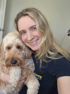 A picture of IzzyLW and her dog. She has long hair, and Rory her spoodle is honey coloured. She is smiling at the camera and Rory is looking like he wants to go back to snoozing. 