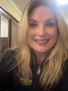 Photograph of EmilyLW.ย She has long blonde hair, a blue LW jumper. She is smiling .